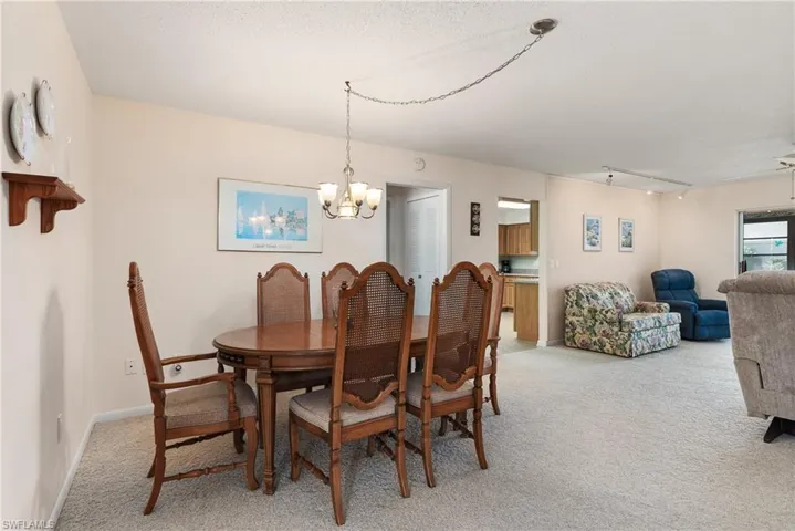 Dining space with light carpet, rail lighting, a chandelier, and a textured ceiling