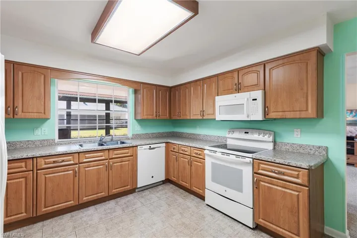 Kitchen featuring white appliances, brown cabinets, and light countertops