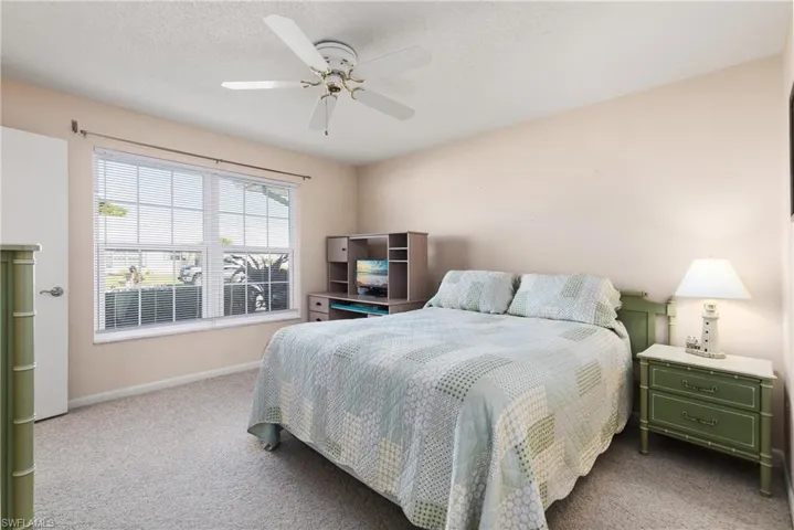 Bedroom with ceiling fan, a textured ceiling, and carpet
