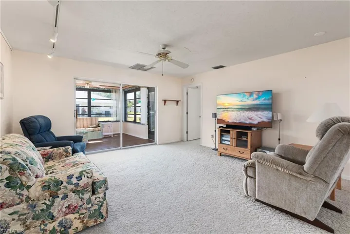 Living room featuring carpet flooring, a textured ceiling, a ceiling fan, and rail lighting