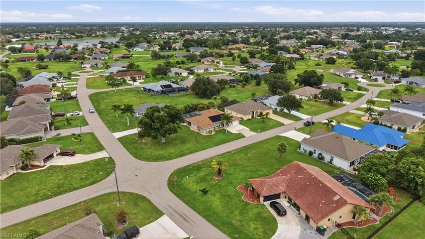 Expansive neighborhood featuring numerous single-story properties with mature trees, paved streets, and a distant body of water