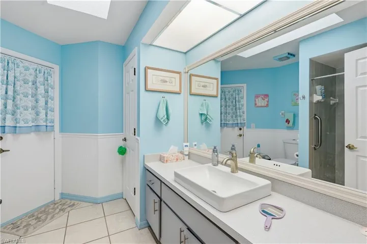 Bathroom featuring a large vanity with an integrated rectangular sink, a wide mirror, and an adjacent shower enclosure with a grab bar