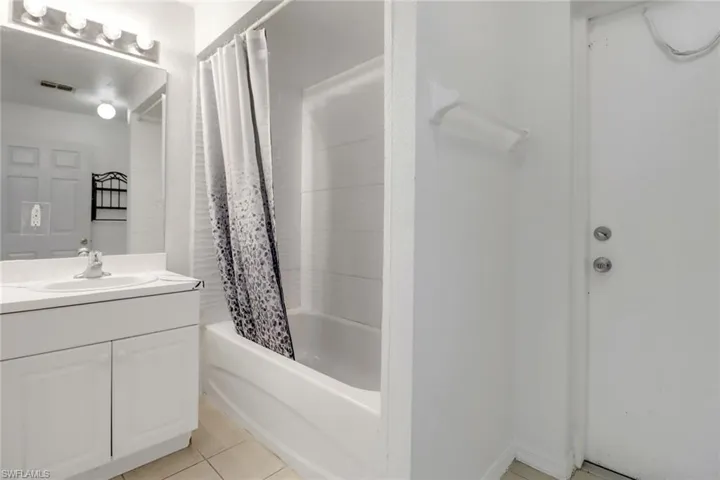 Full bathroom with shower / bathtub combination with curtain, vanity, and tile patterned flooring