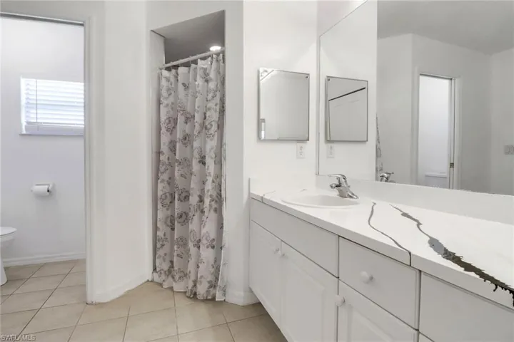 Full bath featuring vanity, tile patterned floors, and curtained shower