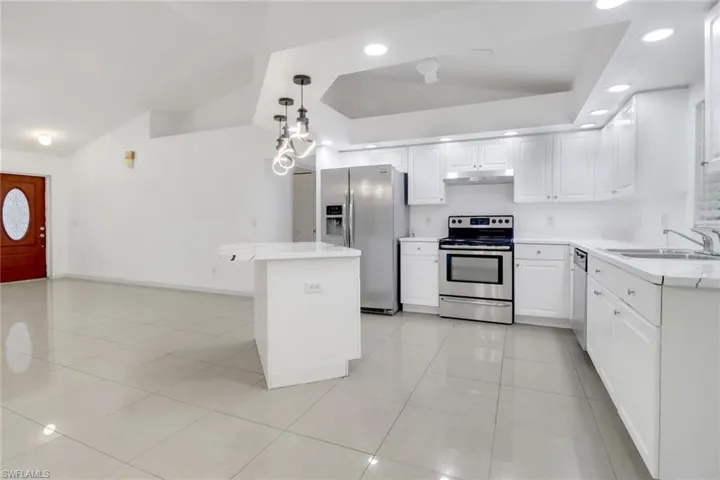 Kitchen featuring appliances with stainless steel finishes, light countertops, light tile patterned floors, white cabinetry, and under cabinet range hood