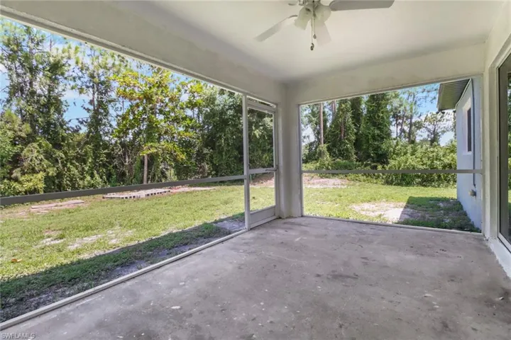 Unfurnished sunroom featuring ceiling fan and view of wooded area
