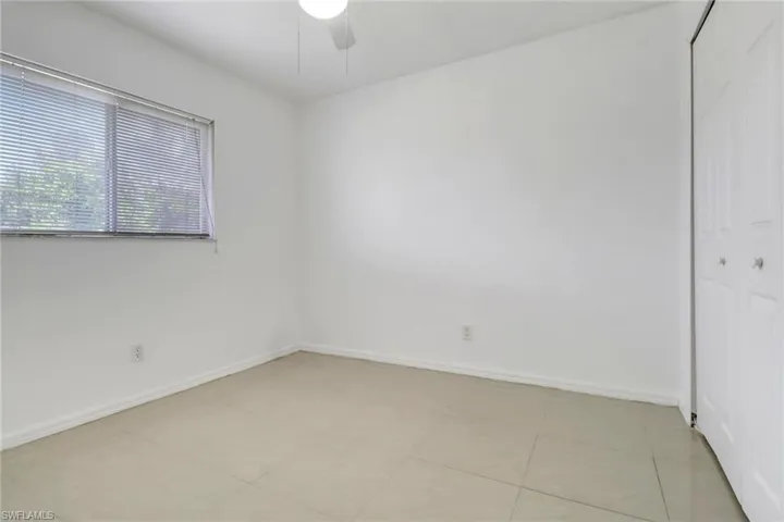 Empty room with a ceiling fan and light tile patterned floors