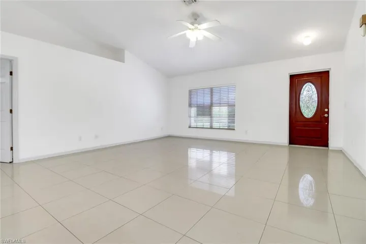 Foyer entrance featuring lofted ceiling, a ceiling fan, and light tile patterned floors