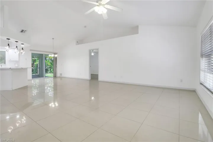 Unfurnished room featuring high vaulted ceiling, light tile patterned flooring, a ceiling fan, and a chandelier