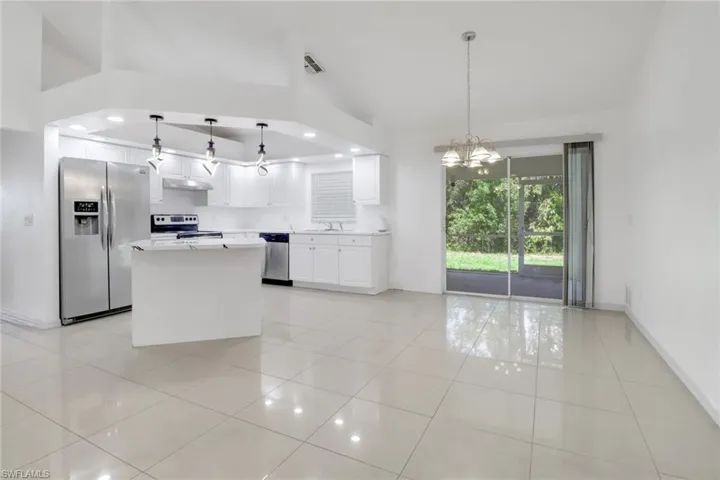 Kitchen featuring appliances with stainless steel finishes, a chandelier, white cabinetry, a kitchen island, and light countertops