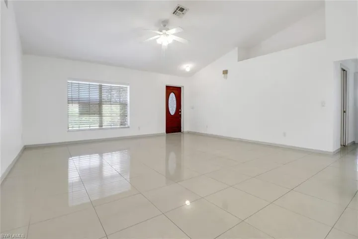 Unfurnished room with ceiling fan, light tile patterned flooring, and high vaulted ceiling