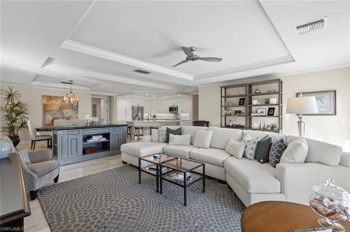 Tiled living room featuring sink, crown molding, ceiling fan, and a raised ceiling
