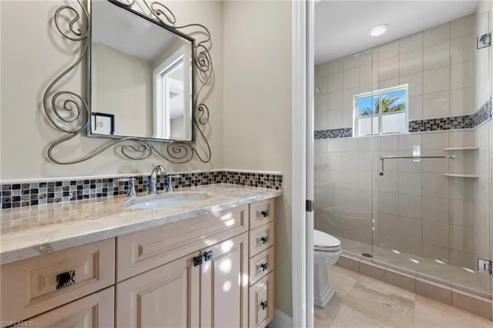 Bathroom with tile patterned flooring, walk in shower, tasteful backsplash, toilet, and vanity