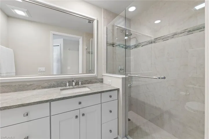 Bathroom featuring vanity, walk in shower, and toilet