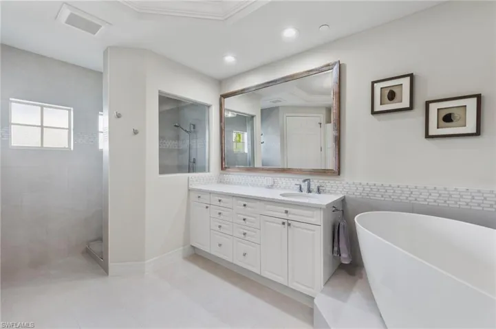 Bathroom with tiled shower, tasteful backsplash, vanity, tile walls, and tile patterned floors