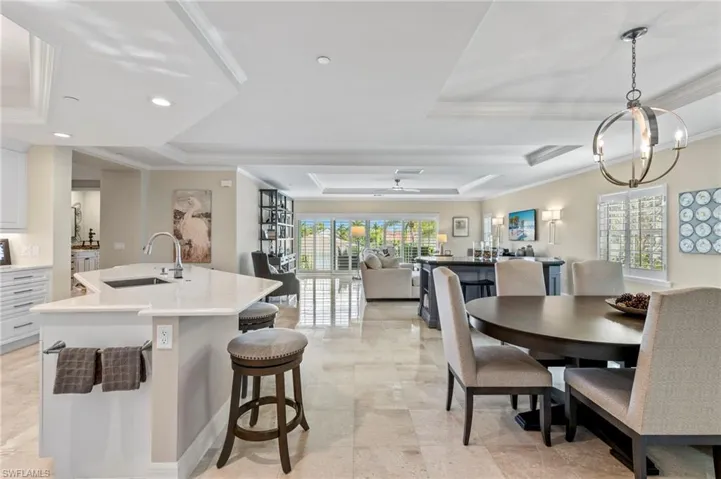Tiled dining space featuring sink, a wealth of natural light, crown molding, and a tray ceiling