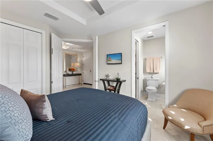 Tiled bedroom featuring a closet, ensuite bath, and ceiling fan