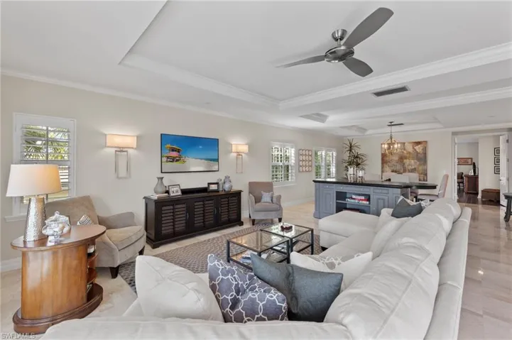 Living room with a tray ceiling, ceiling fan, and ornamental molding