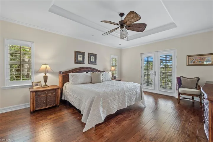 Bedroom featuring dark hardwood / wood-style flooring, multiple windows, and a tray ceiling