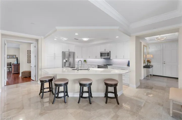 Kitchen with sink, ornamental molding, stainless steel appliances, and light hardwood / wood-style floors