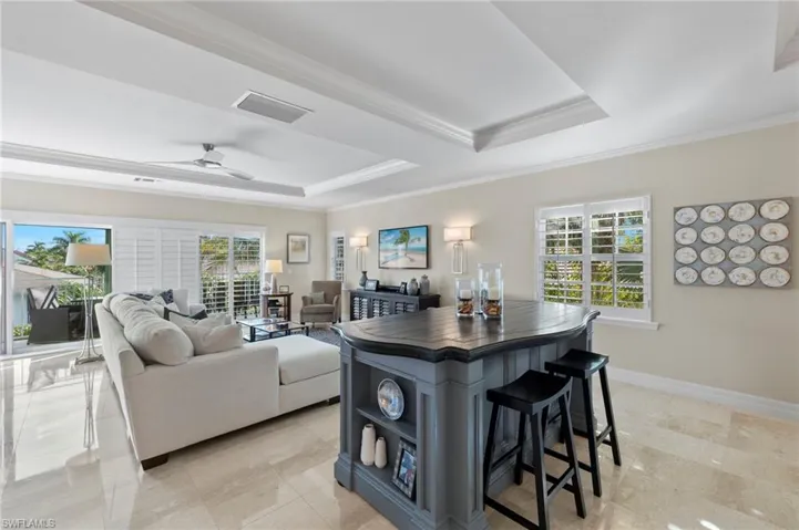 Kitchen featuring a breakfast bar, ceiling fan, a kitchen island, and a tray ceiling