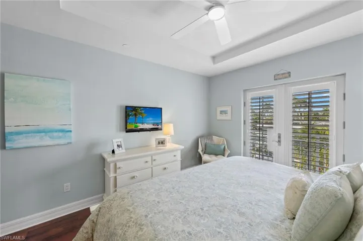 Bedroom with dark hardwood / wood-style floors, a raised ceiling, access to outside, and ceiling fan