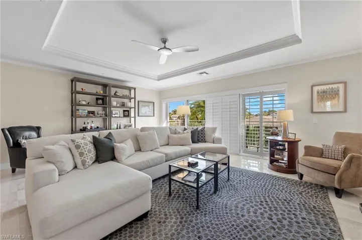 Living room featuring ceiling fan, ornamental molding, and a tray ceiling