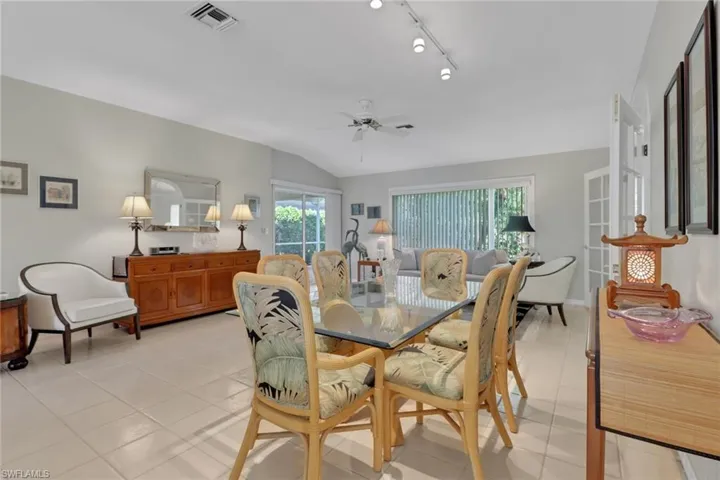 Tiled dining room with rail lighting, lofted ceiling, and ceiling fan