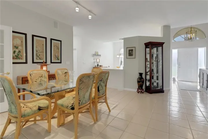 Dining area with an inviting chandelier, track lighting, and light tile patterned floors