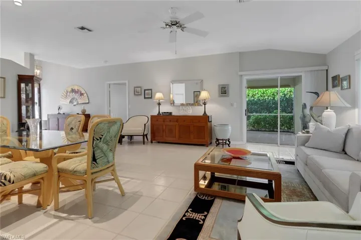 Living room featuring light tile patterned flooring, lofted ceiling, and ceiling fan