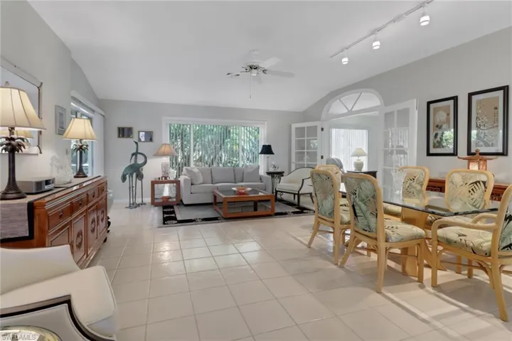 Tiled dining room featuring ceiling fan, rail lighting, and vaulted ceiling
