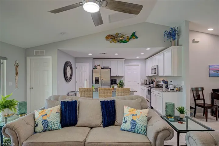 Living room featuring vaulted ceiling, ceiling fan, and recessed lighting