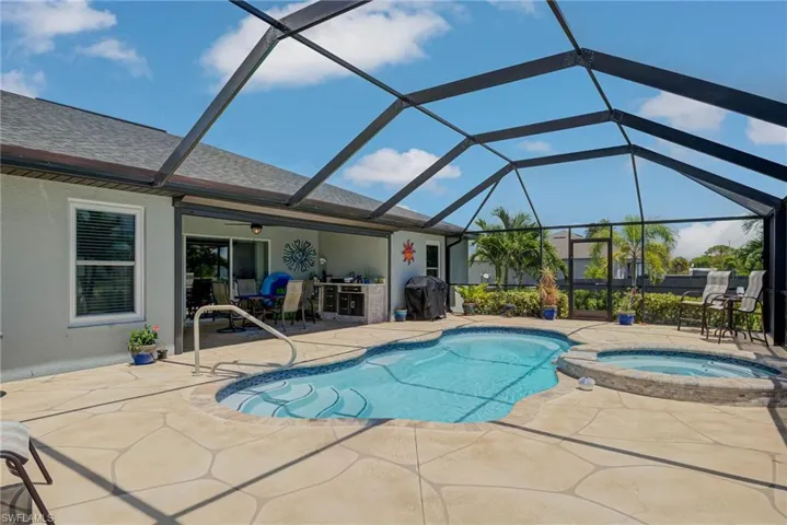 View of swimming pool, a screened in patio, a pool with connected hot tub, and built in grilling area