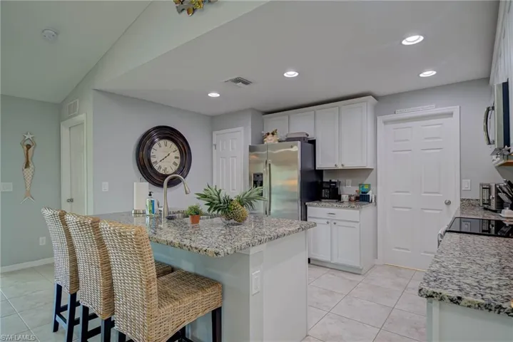 Kitchen with granite countertops, white cabinets, stainless steel appliances, recessed lighting, and a kitchen island