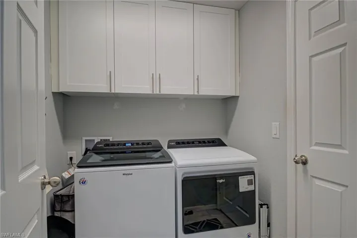 Laundry area featuring upgraded cabinet space and washing machine and clothes dryer