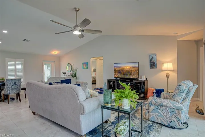 Living room with light tile patterned flooring, vaulted ceiling, and ceiling fan