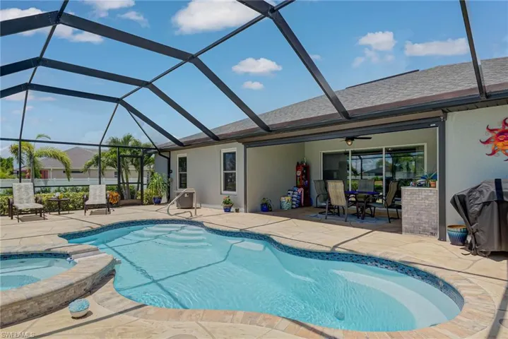 View of swimming pool, a patio, screened enclosure, and a pool with connected hot tub