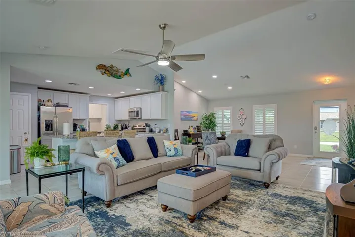 Living area featuring vaulted ceiling, light tile patterned flooring, recessed lighting, and ceiling fan