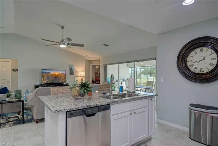 Kitchen with white cabinets, dishwasher,  a large island with sink, and granite countertops