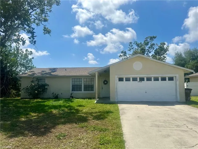 Ranch-style home with an attached garage, driveway, stucco siding, and a front lawn