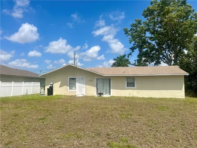Rear view of property with a yard, stucco siding, and fence