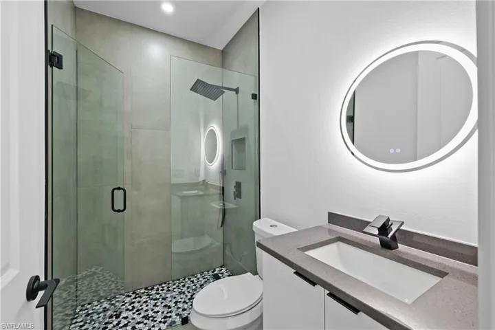 Bathroom with vanity with extensive cabinet space, an enclosed shower, and toilet
