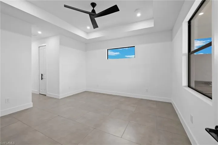 Tiled empty room with a tray ceiling and ceiling fan