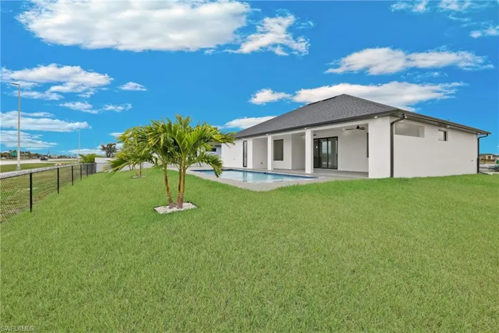 Rear view of house with a patio, a lawn, and a fenced in pool