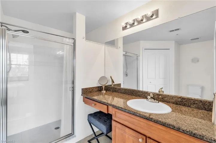 Bathroom with toilet, a shower with door, and vanity