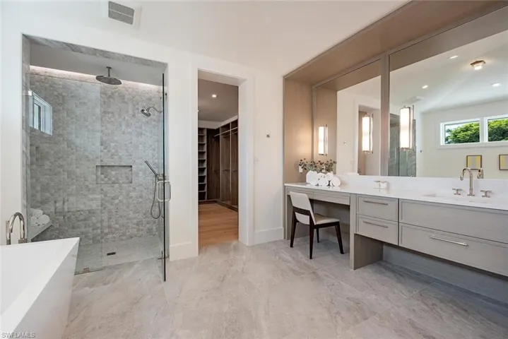Full bath with a spacious closet, visible vents, vanity, a freestanding tub, and a stall shower