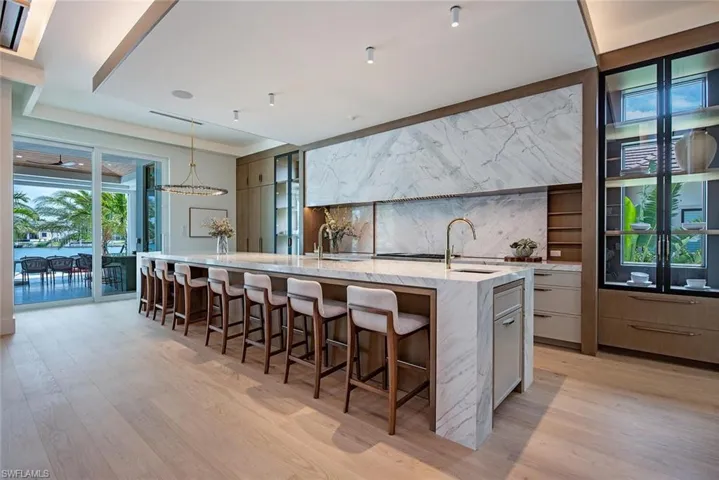 Kitchen with light wood-style flooring, a kitchen breakfast bar, a sink, a large island, and modern cabinets
