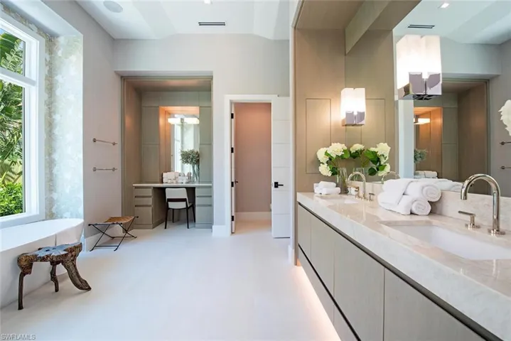 Bathroom featuring visible vents, a soaking tub, a sink, and double vanity