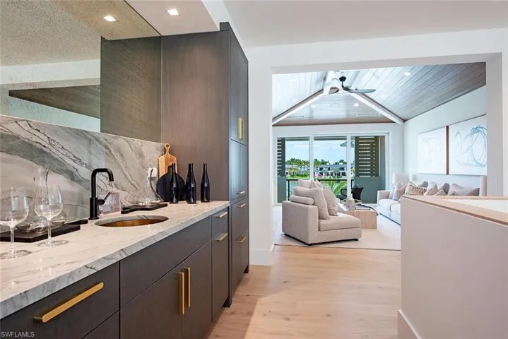 Bar with a sink, tasteful backsplash, light wood-type flooring, wet bar, and recessed lighting