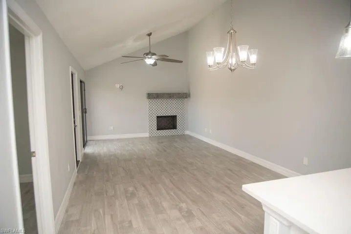 Unfurnished living room with ceiling fan, high vaulted ceiling, light wood-type flooring, and a fireplace